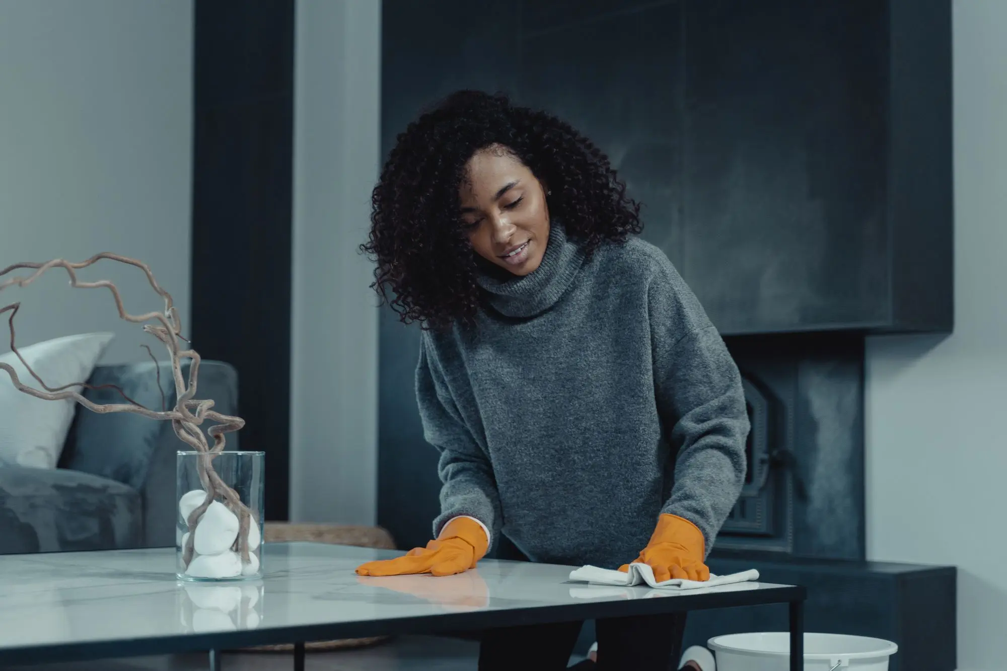 A cleaner in gloves wiping down a table in a modern living room